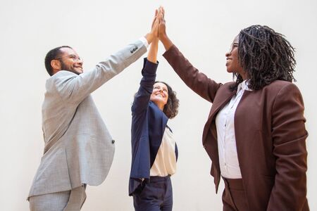 Happy business colleagues enjoying team success. Diverse group of man and women standing over white...