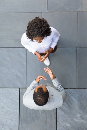 Male business leader instructing female assistant. Top view of business man and woman standing outside, talking and gesturing. Business relationship conceptの写真素材