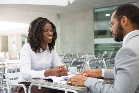 Multiethnic business partners discussing deal in coffee shop. Business man and woman meeting in...