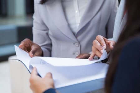 Mid section of business colleagues with folder. Cropped of business people standing together and looking at papers in folder. Teamwork conceptの写真素材