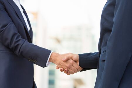 Female business partners meeting outside. Business women in office suits standing and shaking hands. Collaboration conceptの写真素材