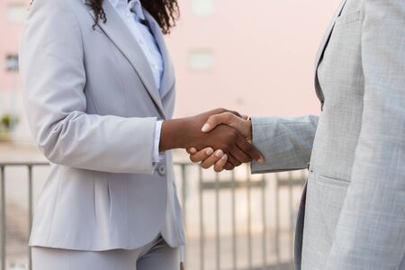 Agent and customer meeting outside. Business man and black woman in office suits standing outside and shaking hands. Cooperation conceptの写真素材