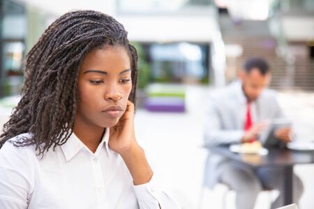 Focused female manager using computer in co-working space. Pensive young African American woman...