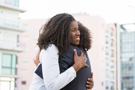 Happy corporate female friends meeting outside. Business women greeting each other in city and...