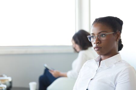 Pensive office employee thinking over work issues during break. Young business woman wearing eyeglasses, looking into vacancy with serious face. Business problem conceptの写真素材