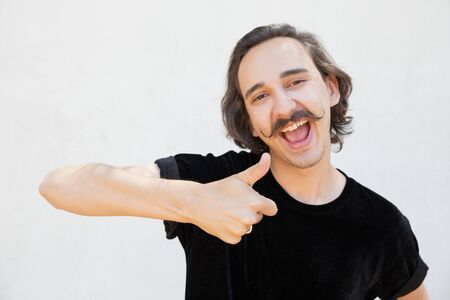 Excited cheerful guy making like gesture. Handsome young man with curly moustache showing thumb up....
