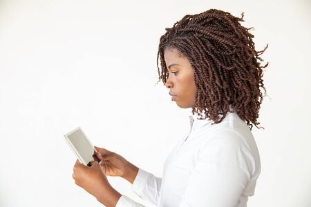 Serious focused professional watching video content on tablet. Young African American business woman...