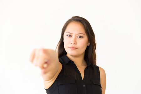 Serious woman pointing at camera. Portrait of beautiful confident young woman pointing with finger...
