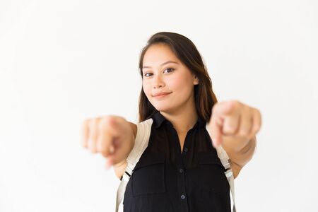 Happy positive teenage girl pointing index fingers at camera. Young Latin woman standing isolated...