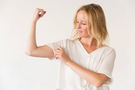 Confident woman showing biceps. Strong young woman showing muscles isolated on grey background. Girl...