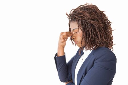 Tired female employee touching face with closed eyes. Young African American business woman posing...