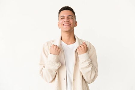 Excited man with closed eyes triumphing. Happy handsome young man triumphing and shaking fists isolated on grey background. Success conceptの写真素材