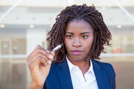 Focused businesswoman writing on glass board. Young African American business woman using pen. Glass board conceptの写真素材