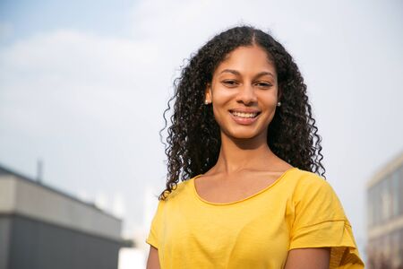 Attractive young woman smiling at camera. Portrait of beautiful cheerful young woman in yellow...