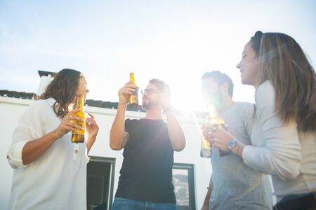 Happy carefree friends drinking beer, dancing and having fun on outdoor terrace. Young men and women in casual meeting outside. Party outside conceptの写真素材