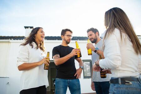 Joyful old friends celebrating great event on outdoor terrace. Young men and women in casual meeting outside. Beer party outside conceptの写真素材