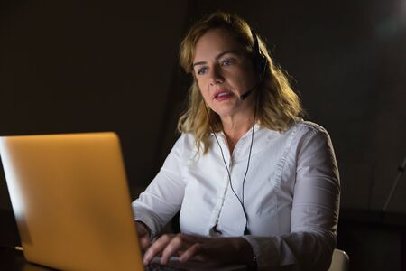 Businesswoman in headset using laptop computer. Professional female call center operator in headset...