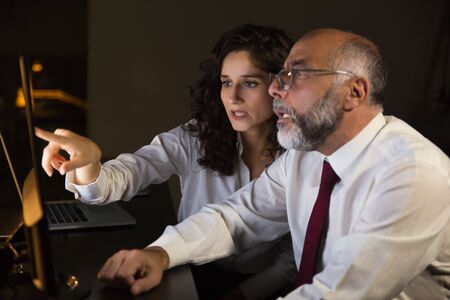 Businessman and businesswoman working with computer. Side view of focused male and female business...