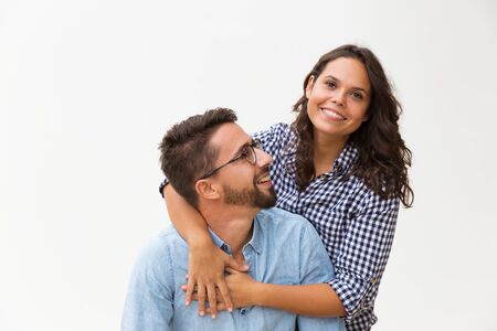 Happy sweet couple having fun, hugging and posing. Young woman in casual and man in glasses standing...