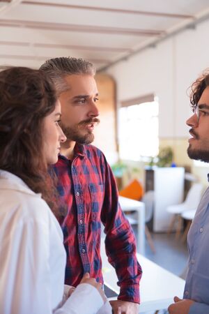 Startup team having short brainstorming set, standing in circle, talking. Business colleagues in...