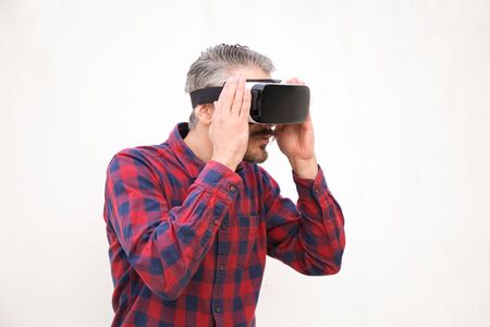 Handsome bearded man in VR headset. Focused man in checkered shirt using virtual reality headset on...