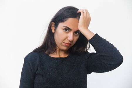 Puzzled serious woman touching head, looking at camera, suffering from headache. Beautiful young...
