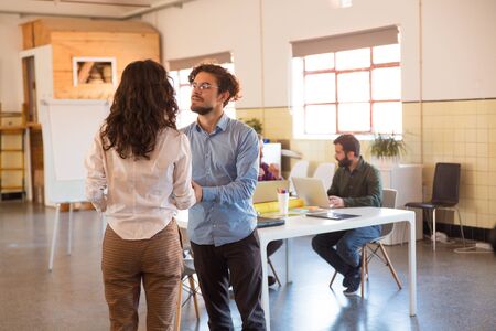 Male and female employees discussing work issues in meeting room. Business colleagues in casual...