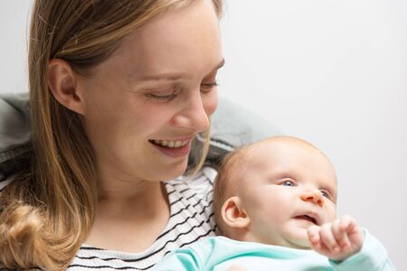 Closeup of happy positive new mother holding adorable baby. Portrait of young woman and cute little...