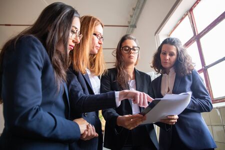 Low angle shot of concentrated business team reading document. Group of focused women looking at new project. Teamwork conceptの写真素材