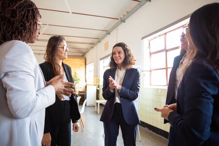 Confident mature employee talking with younger colleagues. Cheerful office managers talking in office. Communication conceptの写真素材
