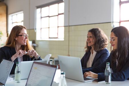 Smiling businesswomen working with laptops. Group of professional multi ethnic businesswomen sitting...