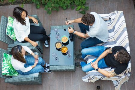 Young man opening wine bottle. Cheerful friends spending time together. Friendship concept