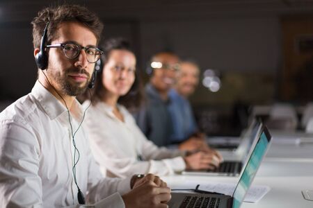 Confident bearded call center operator looking at camera. Handsome young man posing at workplace....