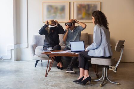 Excited mature people wearing VR glasses. Confident young woman introducing new product with help of virtual reality headsets. Technology conceptの写真素材