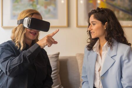Excited woman tester experiencing VR headset. Smiling Caucasian young woman explaining how to use...
