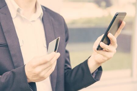 Businessman paying for online purchase by credit card. Man in office suit holding smartphone and credit card. Internet shopping or online payment conceptの写真素材