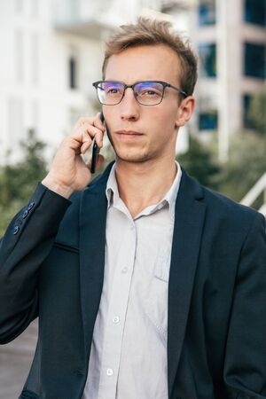 Serious focused business man talking on cell outside and listening carefully. Stressed professional...