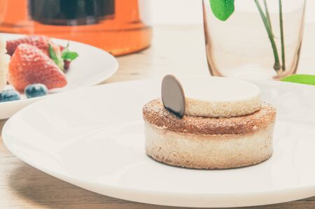 Closeup of cakes portions, berries, glass and teapot on table. Delicious pastries and teapot with tea on wooden table. Breakfast or dessert concept.の写真素材