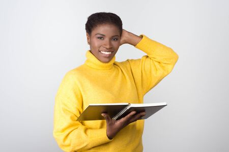 Smiling African American student with notepad. Cheerful young lady with open notebook looking at...