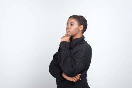 Thoughtful African American woman holding hand on chin. Pensive young lady looking at distance. Thinking conceptの写真素材
