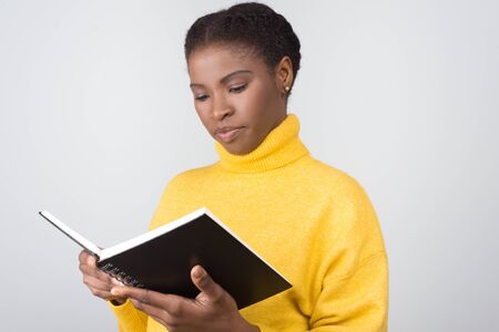 Beautiful confident student reading information from notepad. Attractive young lady with open notebook. Education, tuition conceptの写真素材