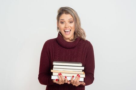 Excited young woman holding books. Beautiful cheerful young blonde woman holding pile of books and...