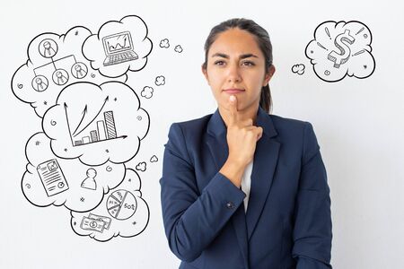 Thoughtful young businesswoman with hand drawn business sketches. Portrait of pensive young woman in formal wear holding finger on chin isolated on background with icons. Emotion conceptの写真素材