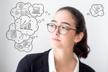 Young woman looking away with hand drawn business sketches. Portrait of confident Caucasian businesswoman or student wearing glassesの写真素材