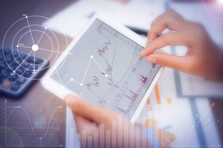 Trader using tablet with financial analysis graphs. Closeup of person working with candlestick...