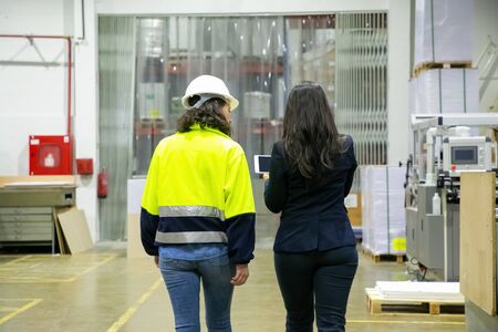Back view of technician and manager walking at printing house. Concentrated factory workers strolling at plant. Print manufacturing conceptの写真素材