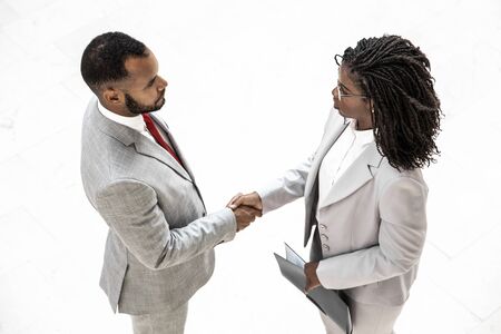 Business partners closing deal. Top view of diverse business man and woman standing and shaking hands. Partnership conceptの写真素材