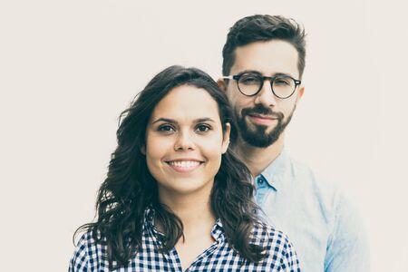 Positive guy in casual standing behind his beautiful girlfriend. Young woman in casual and man in...