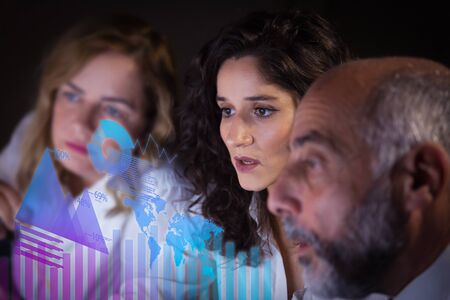 Focused business colleagues and virtual statistic graphics. Close-up view of serious professional...