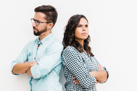Annoyed upset couple standing back-to-back with arms crossed. Young woman in casual and man in...
